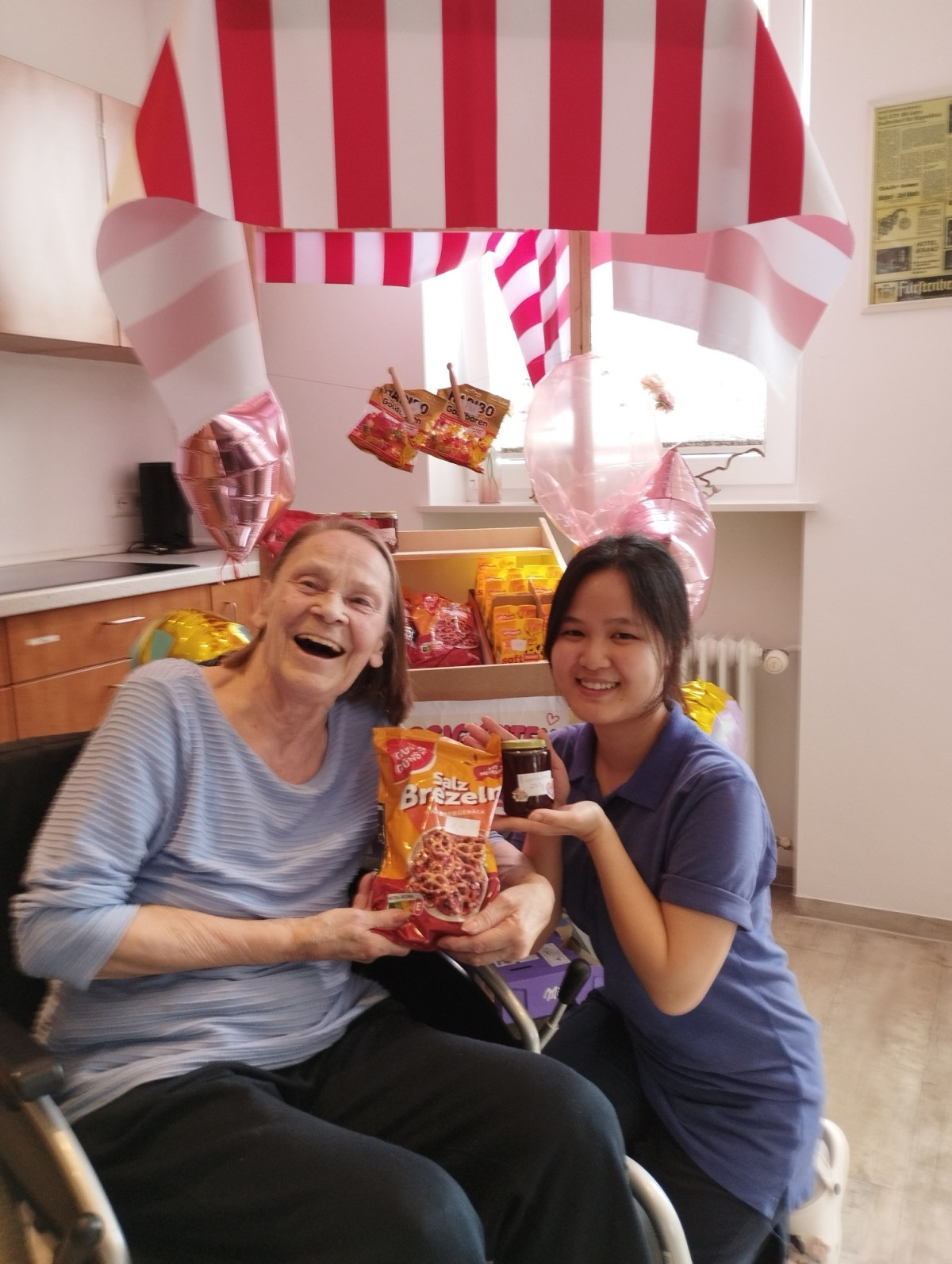 Zwei Frauen lachen fr&ouml;hlich in die Kamera und halten gemeinsam eine Packung "Brezel'ly" hoch.