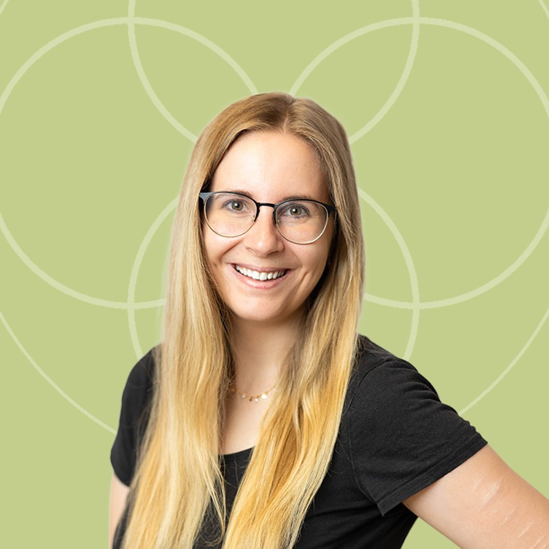 Eine Frau mit langen blonden Haaren und Brille l&auml;chelt freundlich in die Kamera.