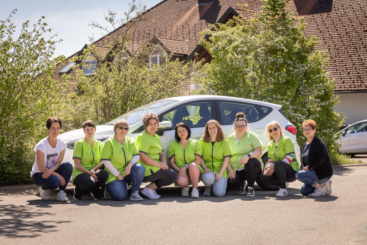 Ambulante Pflegeteam vor wei&szlig;em Auto.