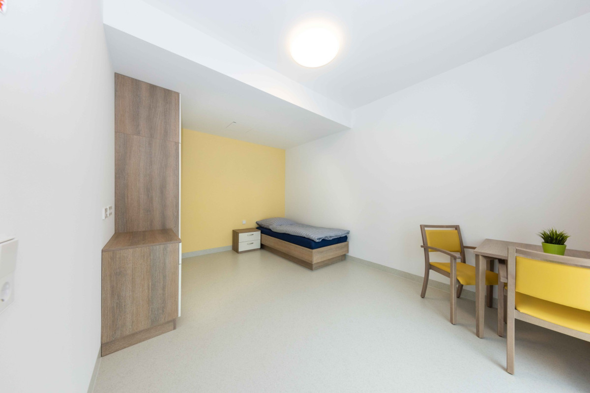 Helles Zimmer mit Bett, Schreibtisch und Stuhl.