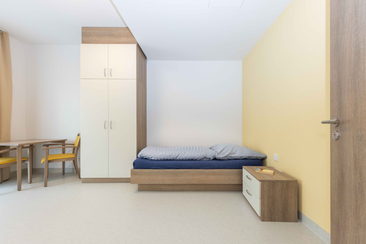 Modernes Schlafzimmer mit Holzm&ouml;beln und gelber Wand.
