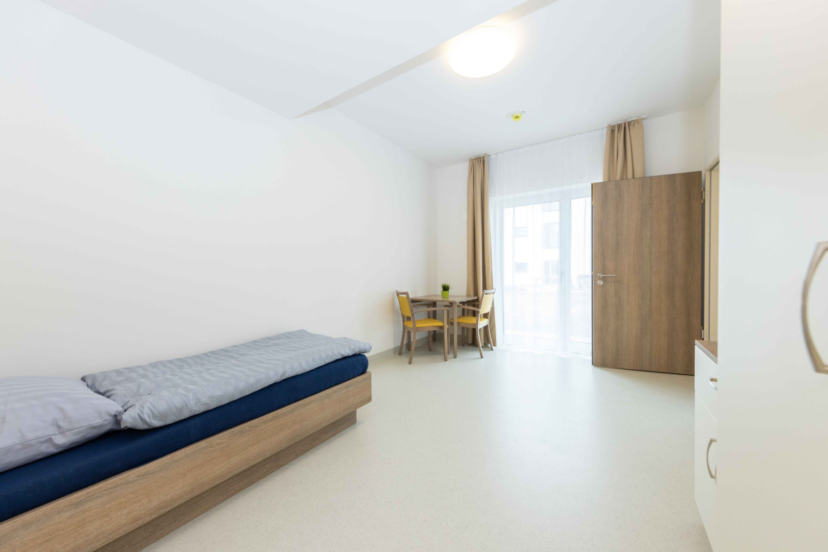 Helles Zimmer mit Bett und Sitzbereich.