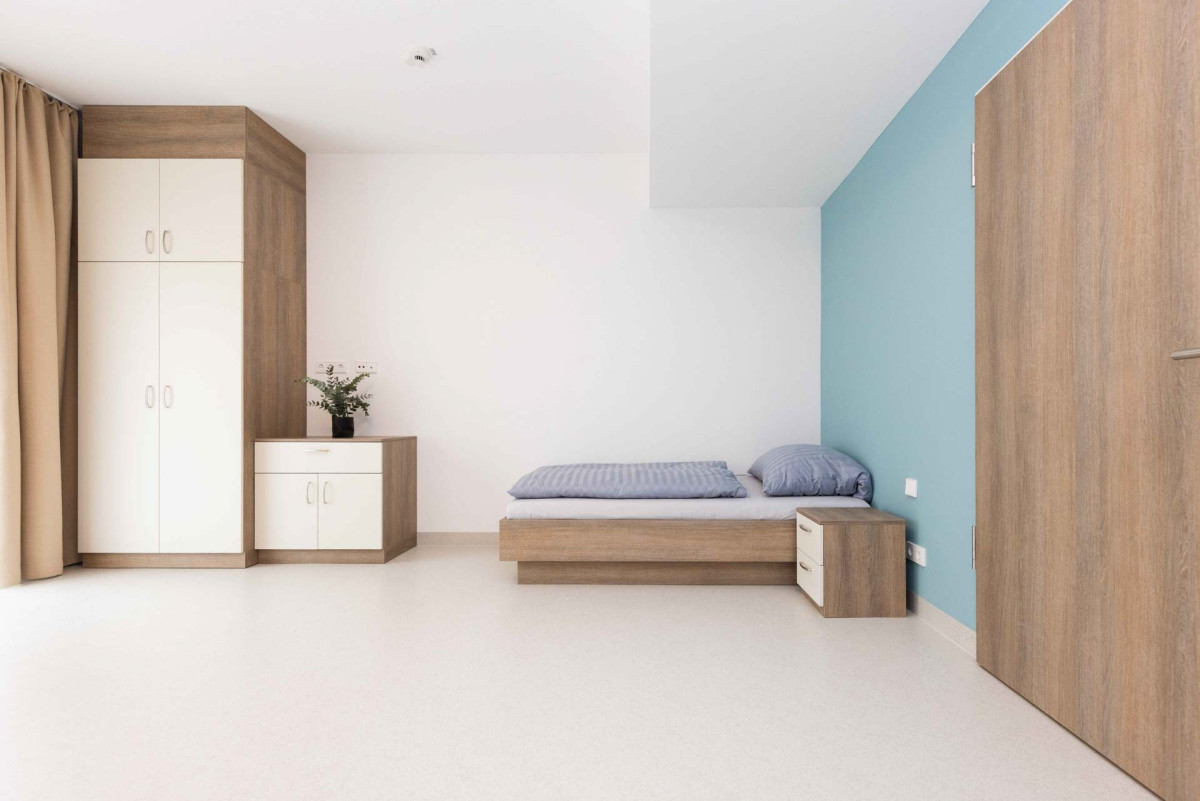 Modernes Schlafzimmer mit Holzm&ouml;beln und blauer Wand.