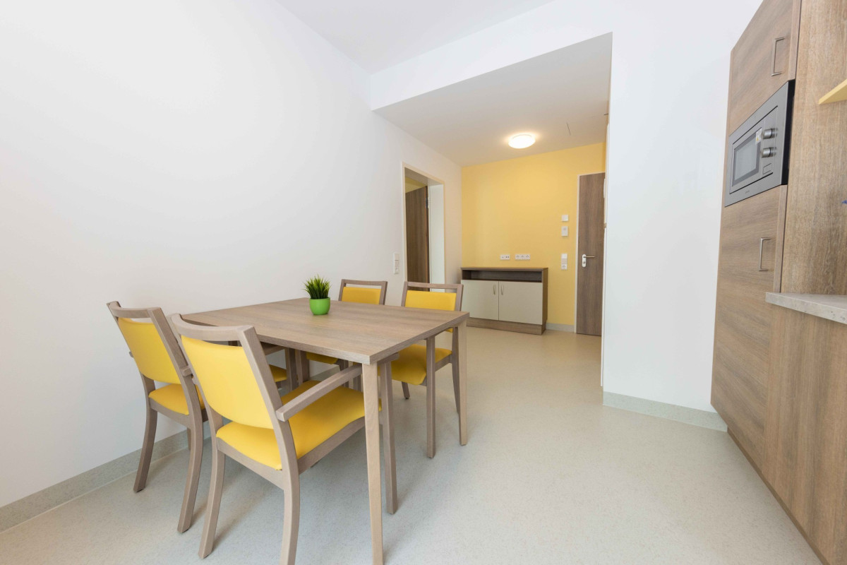 Helles Esszimmer mit Holztisch und gelben St&uuml;hlen.