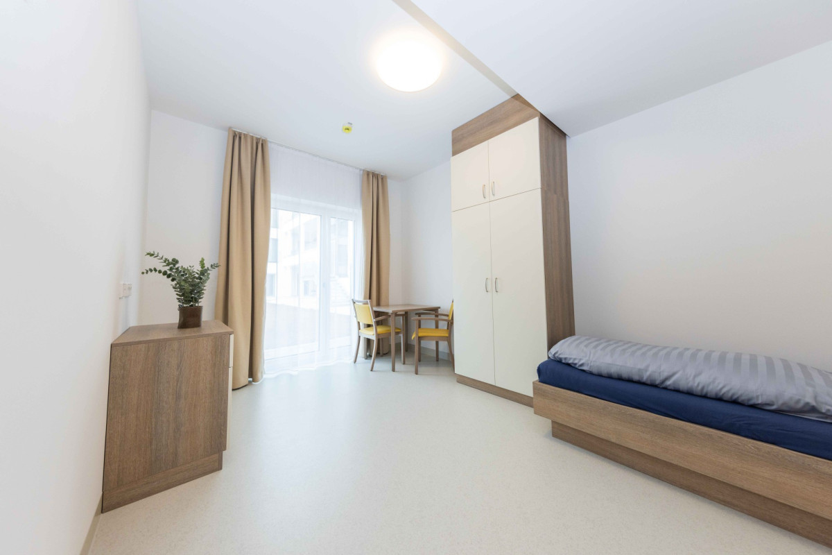 Helles Wohnzimmer mit Bett, Schrank und Essbereich.
