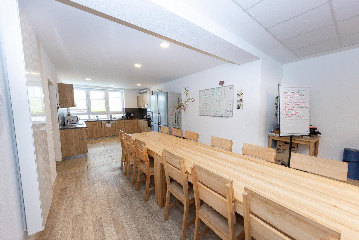 Helles Wohnzimmer mit Holztisch und St&uuml;hlen.