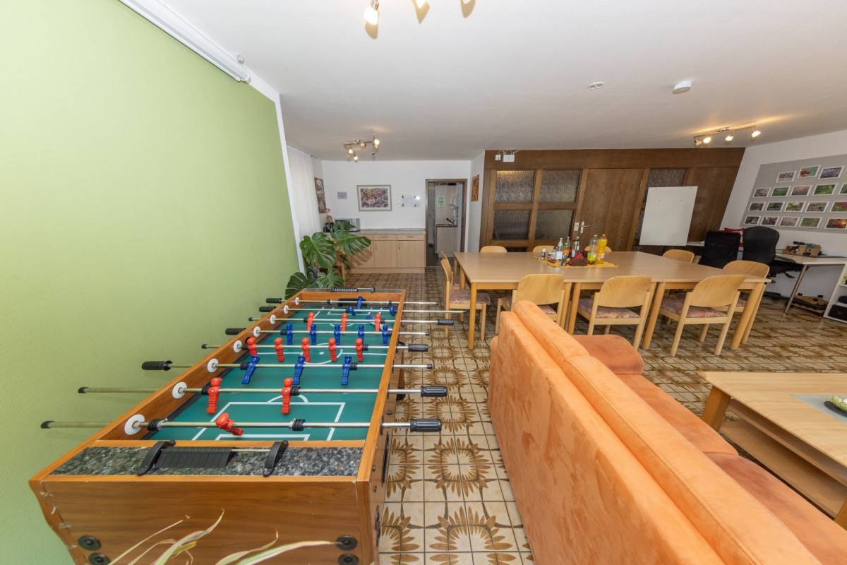 Gemeinschaftsraum mit Tischfu&szlig;ball und Esstisch.