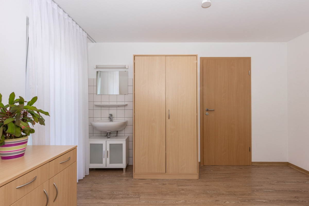 Helles Zimmer mit Holzm&ouml;beln und Bad.
