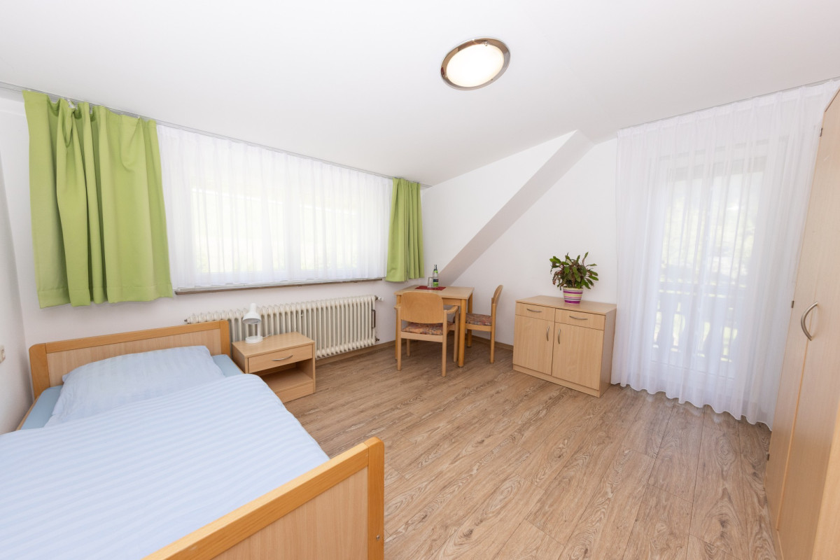 Helles Schlafzimmer mit Einzelbett und Holzm&ouml;beln.