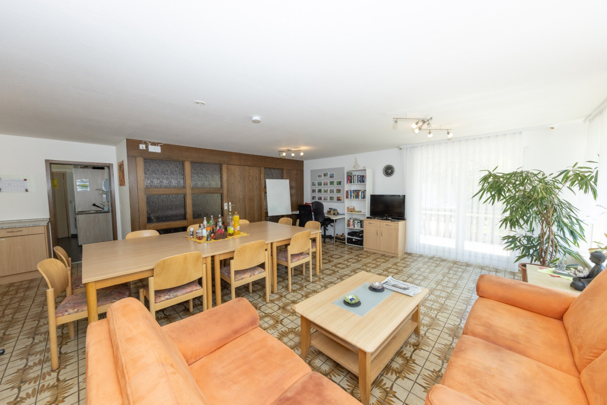 Gro&szlig;z&uuml;giges Wohnzimmer mit Esstisch und Sofas.
