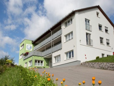 Haus Berghof mit gr&uuml;nem Eingang und Wiese.