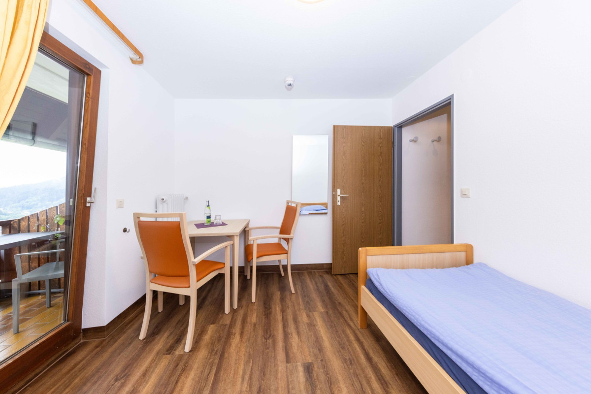 Helles Hotelzimmer mit Bett, Tisch und St&uuml;hlen.