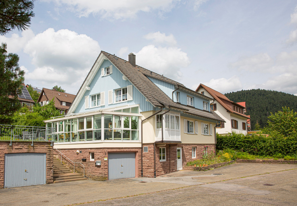 Gro&szlig;es Wohnhaus mit Glasveranda und Garagen.