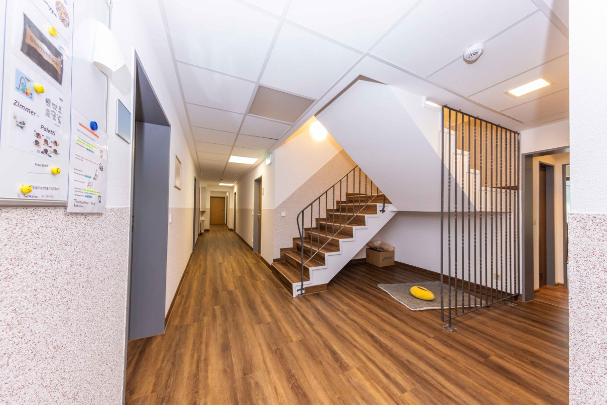 Heller Flur mit Holzboden, Treppe und Gel&auml;nder.