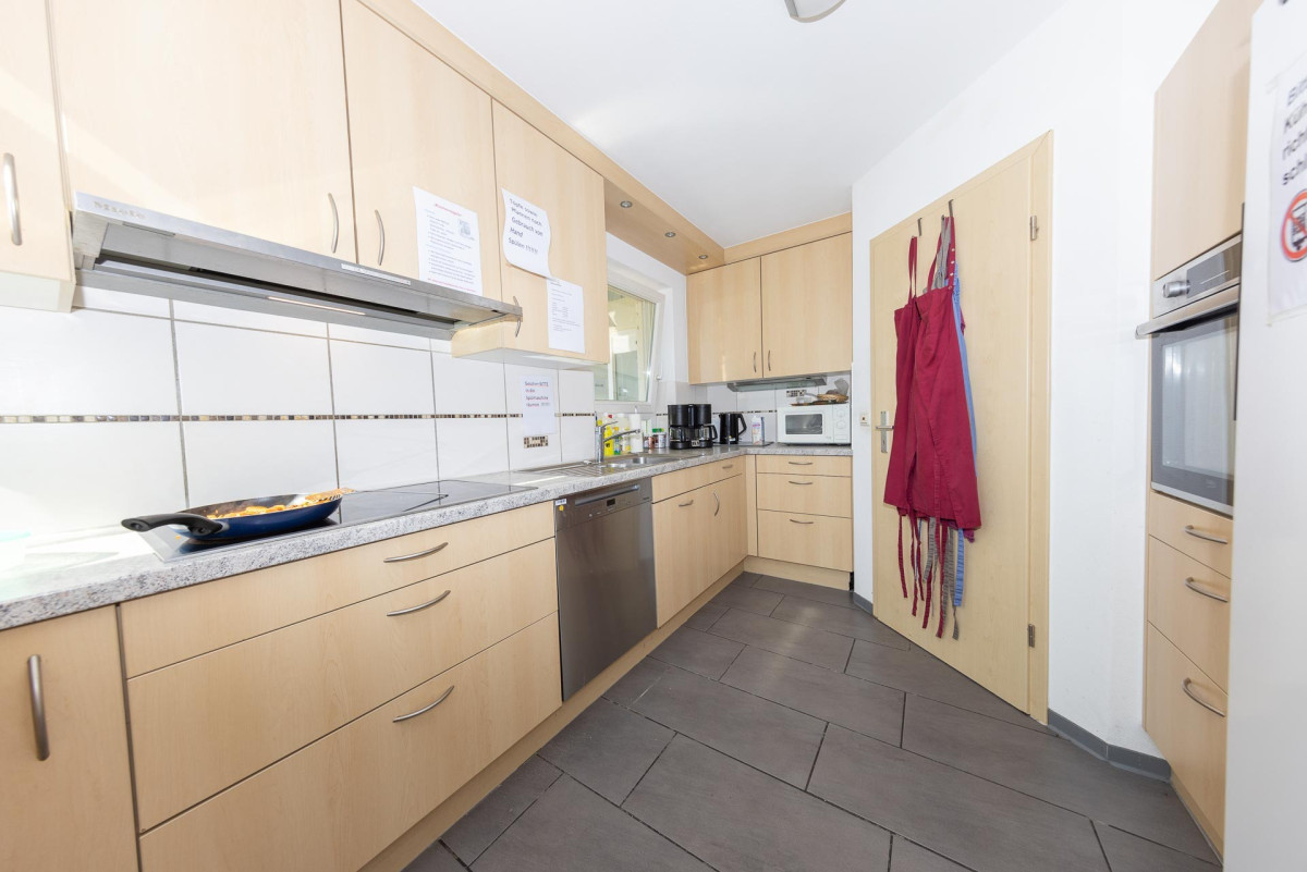 Moderne K&uuml;che mit Holzschr&auml;nken und dunklem Fliesenboden.