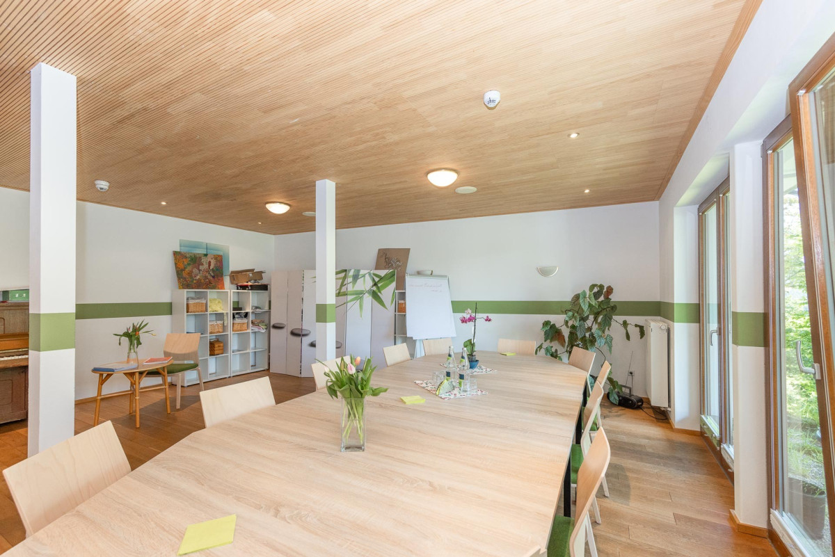 Helles B&uuml;ro mit Holzdecke, gr&uuml;nem Wandstreifen und Pflanzen.