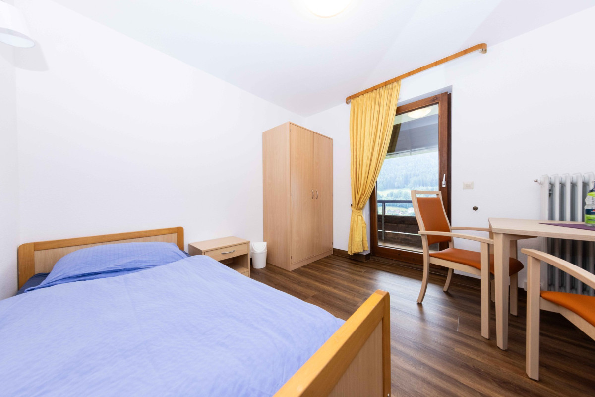 Helles Schlafzimmer mit Holzbett und Schreibtisch.