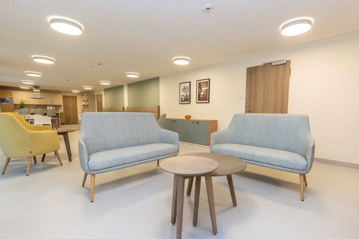 Modernes Wartezimmer mit zwei blauen Sofas und rundem Tisch.