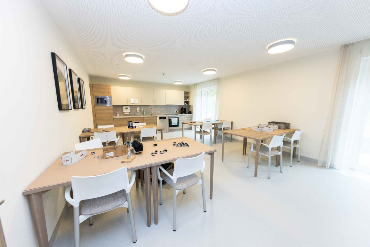 Helles B&uuml;ro mit Holztischen und wei&szlig;en St&uuml;hlen.