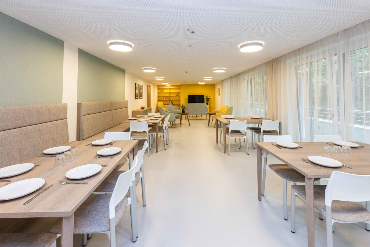 Helles Speisezimmer mit Holztischen und St&uuml;hlen.