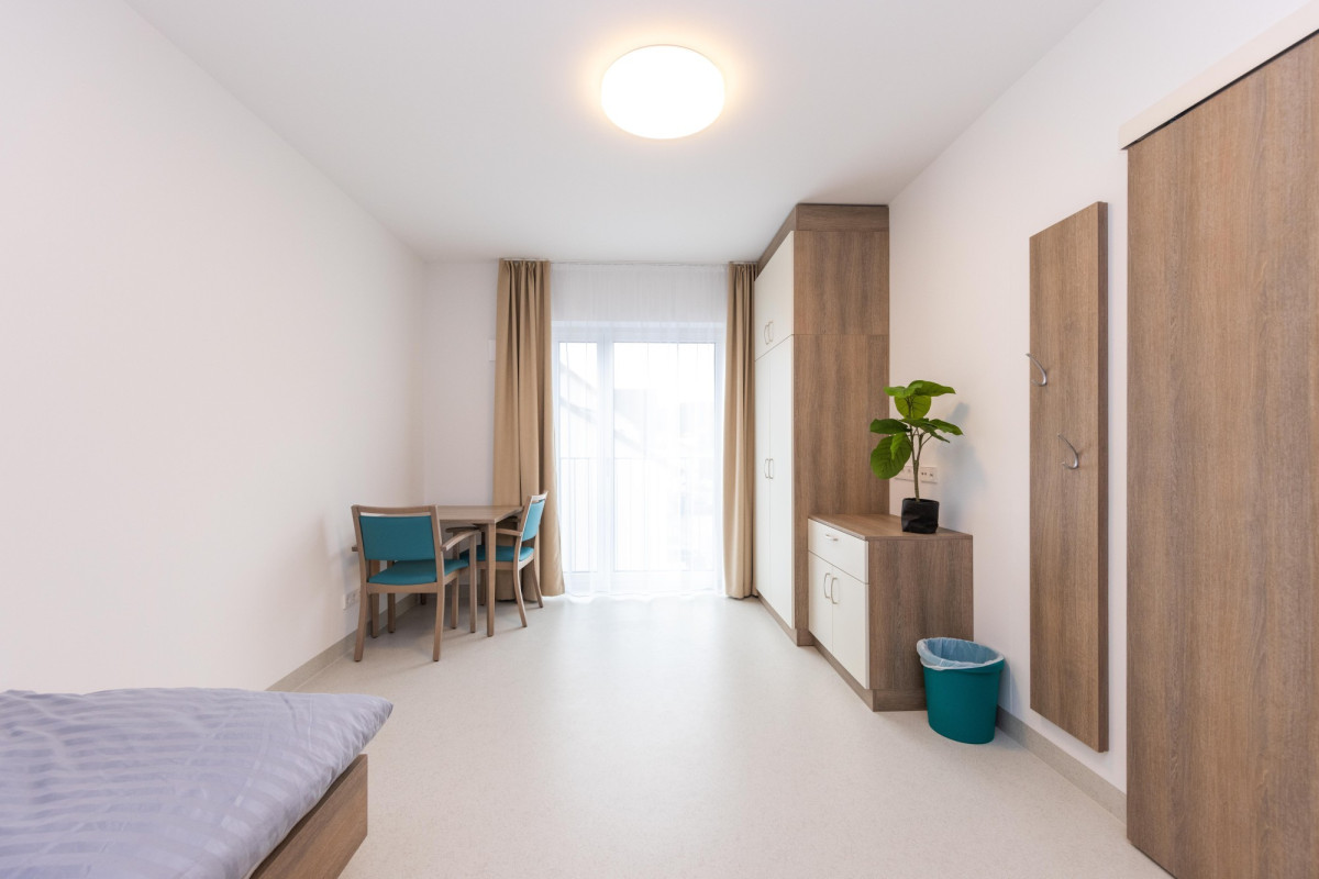 Helles Zimmer mit Bett, Tisch und Holzm&ouml;beln.