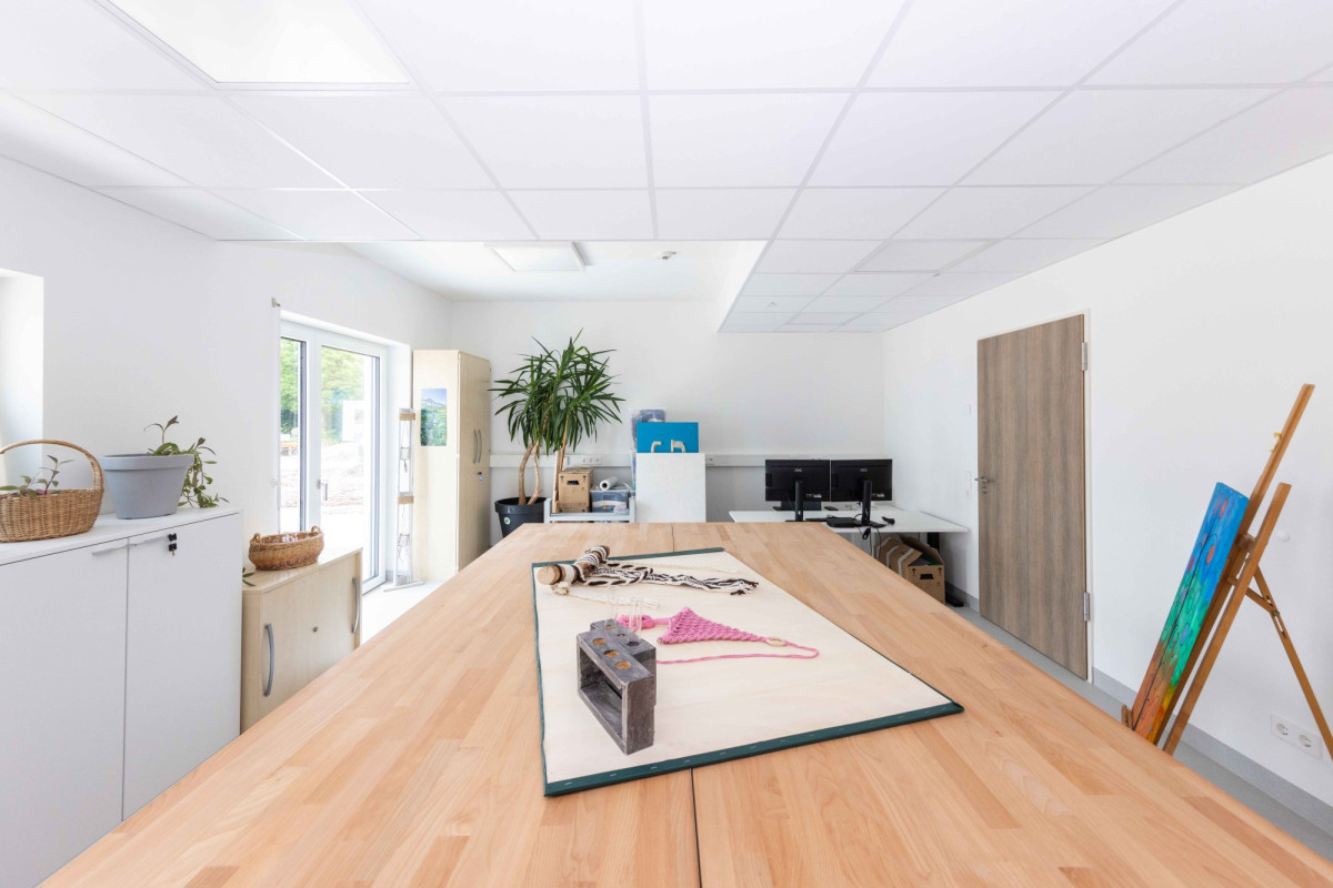 Helles B&uuml;ro mit Holztisch und Kunstmaterialien.