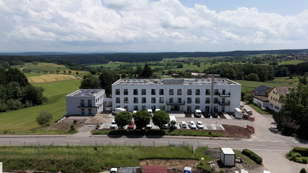 Haus Weitblick, modernes wei&szlig;es Geb&auml;ude in gr&uuml;ner Landschaft.