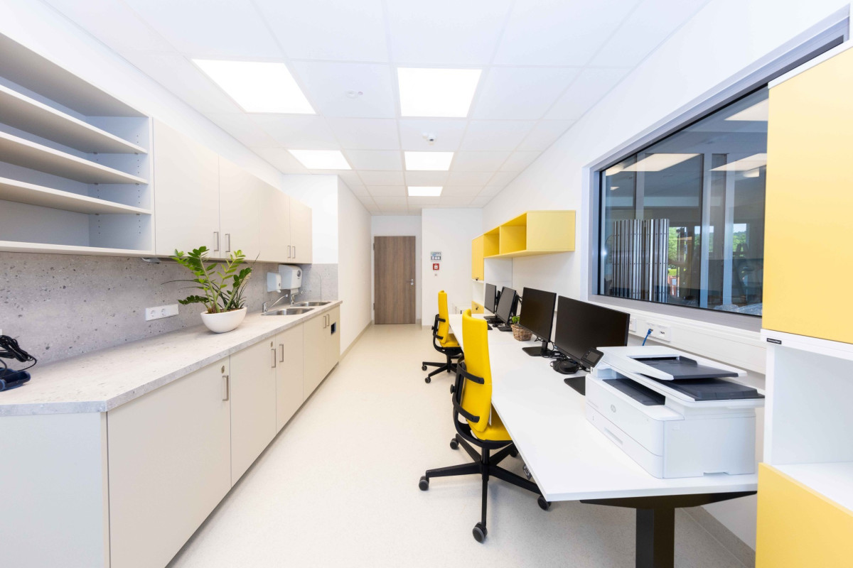 Modernes B&uuml;ro mit gelben Akzenten und K&uuml;che.