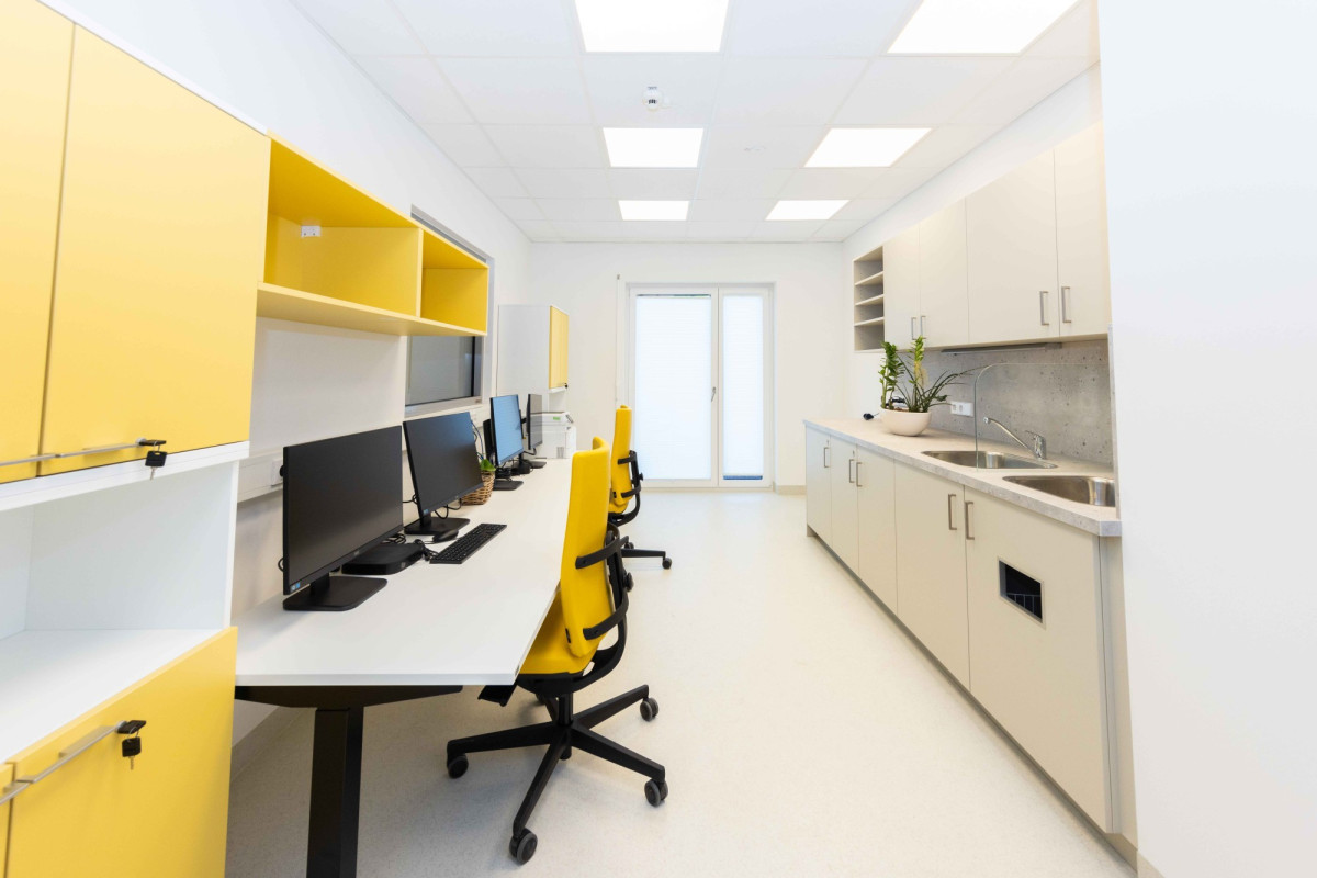 Modernes B&uuml;ro mit gelben M&ouml;beln und K&uuml;che.
