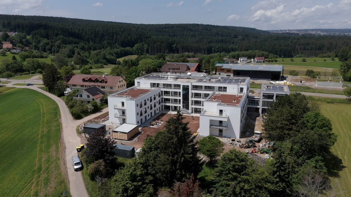 Luftaufnahme eines modernen Wohngeb&auml;udes in gr&uuml;ner Landschaft.
