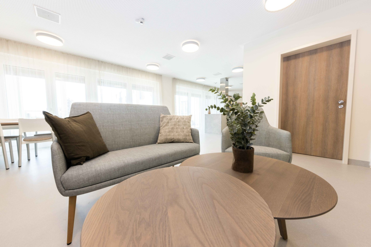 Modernes Wohnzimmer mit grauem Sofa und rundem Tisch.
