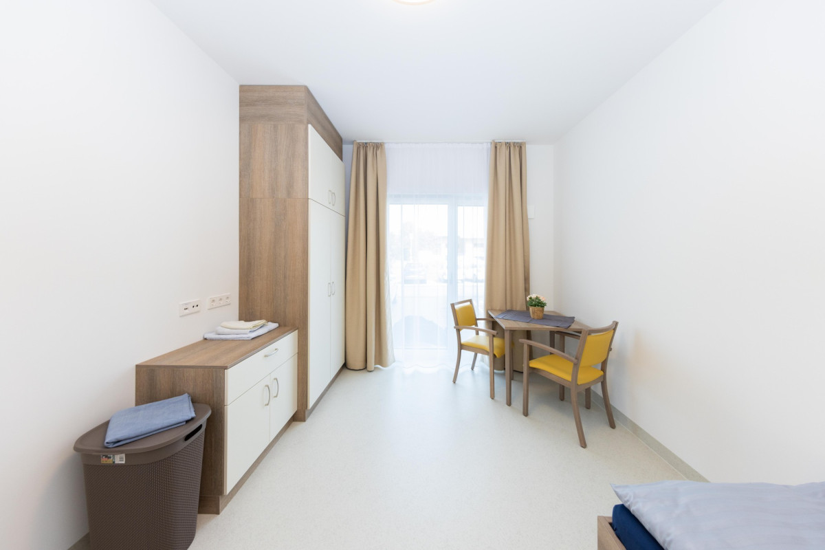 Modernes Hotelzimmer mit Holzm&ouml;beln und gelben St&uuml;hlen.