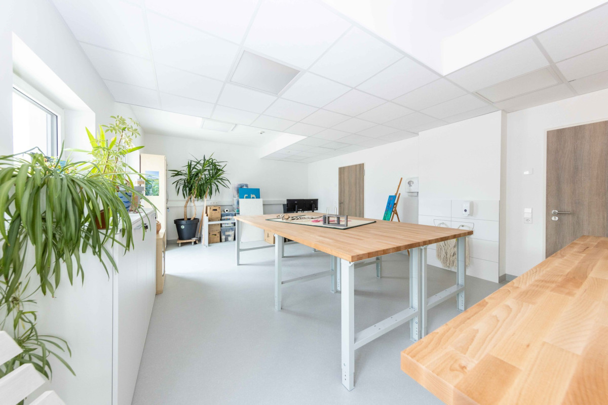 Helles B&uuml;ro mit Holztischen und Pflanzen.