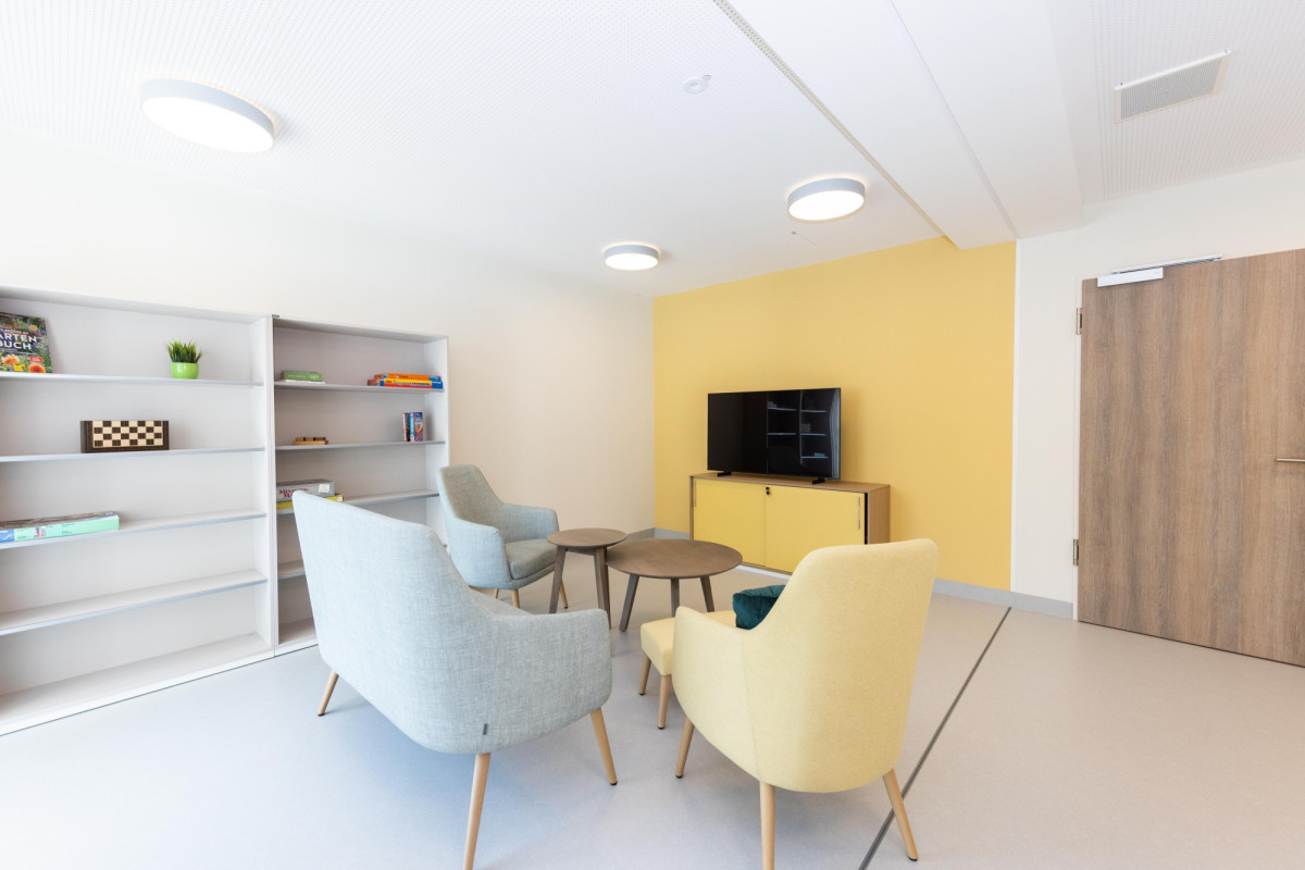 Modernes Wohnzimmer mit gelber Akzentwand und M&ouml;beln.
