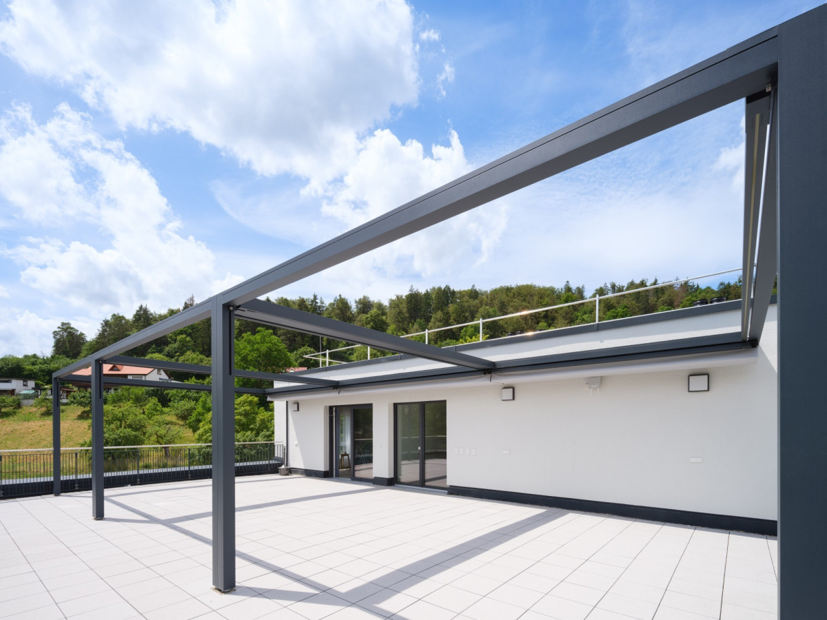 Modernes Geb&auml;ude mit grauer Pergola und heller Terrasse.
