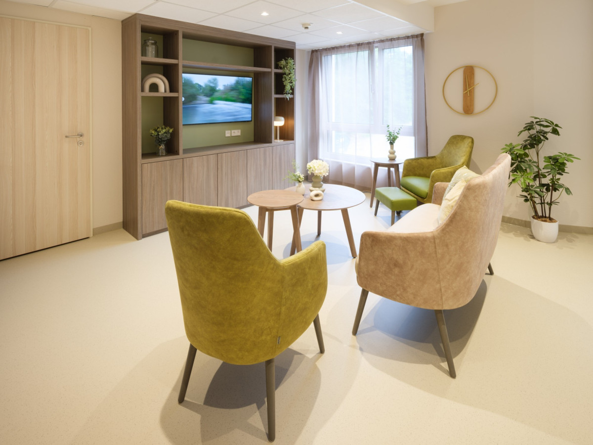 Modernes Wohnzimmer mit gr&uuml;nen Sesseln und Fernseher.
