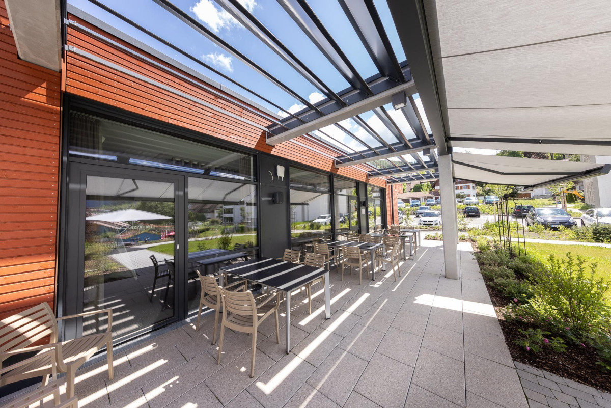 Moderne Terrasse mit Pergola und Sitzbereichen.