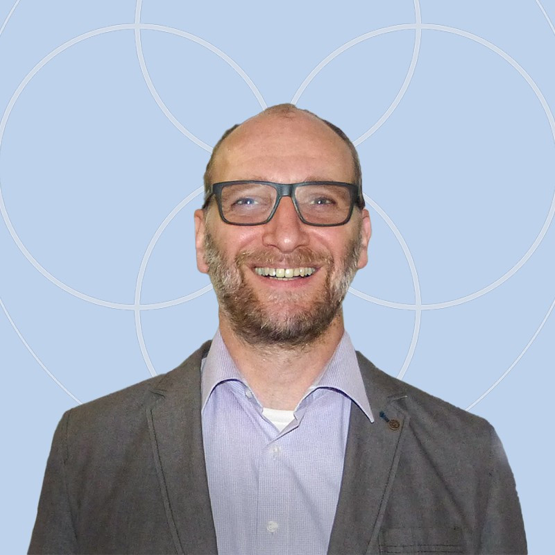Mann mit Brille und Bart l&auml;chelt.